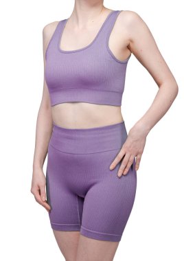 Formda bir kadının sırtından atölye çekiminde, gri çatallı, pürüzsüz spor şortu ve uyumlu spor sutyeni sergileniyor. Kumaş desenli bir örgü. Beyaz arka planda izole edilmiş. Spor giyim, spor giyim ve fitness programları için ideal.