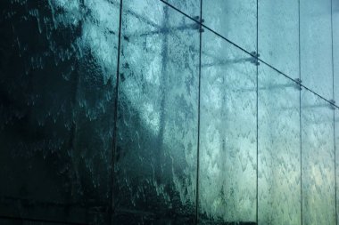 Işıkla aydınlatılan bir su akıntısı, camdan akan bir su akıntısı.