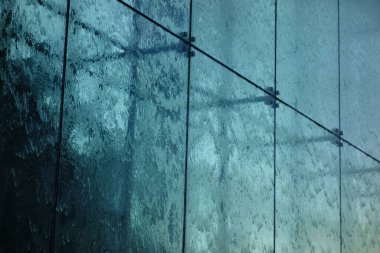 Işıkla aydınlatılan bir su akıntısı, camdan akan bir su akıntısı.