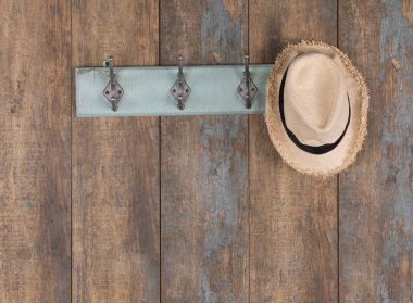 Tahta duvarda hasır şapkalar olan eski ahşap bir askı.