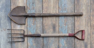 Ahşap bir arka planda köy bahçe aletleri, kürek, yaba.