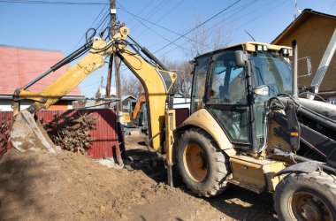 Bir kazıcı kanalizasyon boruları için çukur kazıyor