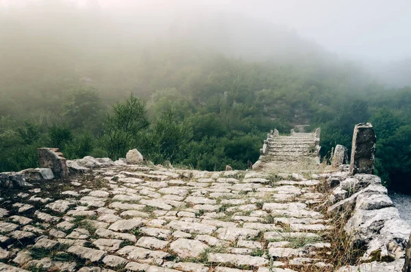 Sis ve Plakidas 'ın antik taş köprüsü şafak vakti kurak bir nehrin yatağının üzerinde. Zagori bölgesi, Yunanistan Vikos Vadisi Ulusal Parkı.