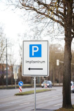 Covid Aşı Merkezi 'nin Alman mesajına işaret eden bir caddedeki park levhası.