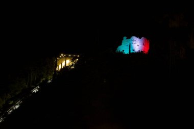 İtalya 'daki Riva del Garda kasabasının tepesindeki dağda aydınlatılmış gözetleme kulesi.