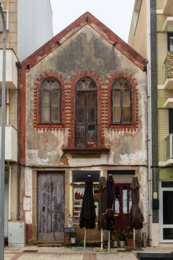 Kırmızı tuğla pencere çerçeveleri ve boyalı eski püskü bir ev, Portekiz, Ovar Furadouro, 9.10.2025.