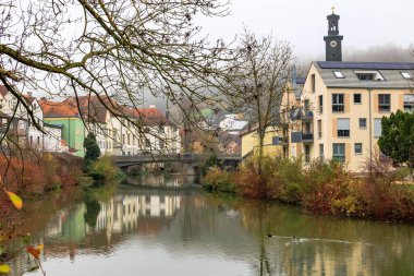 Altmhl nehri üzerinde renkli evlerin ve kilise kulesinin yansımasıyla, Almanya, Eichsttt, 7 Kasım 2025.