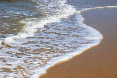 Yuvarlanan dalga, güneş ışığı altındaki kıyı şeridinde köpüklü desenler oluşturuyor Portekiz, Ovar Furadouro, 10.10.2025.