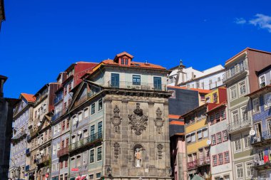 Açık mavi gökyüzü altındaki geleneksel Ribeira binalarıyla çevrili süslü taş cephe, Portekiz, Porto, 11 Ekim 2025