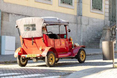 Tarihi mimari, Portekiz, Porto, 11 Ekim 2025 'te dar kaldırım taşı caddelerinden geçen antika kırmızı klasik tur aracı.