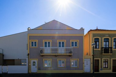 Portekiz 'in kıyı kasabası Torreira' da 13 Ekim 2025 'te mavi azulejo fayans cephesi ve parlak güneş ışığı altında balkonu olan geleneksel Portekiz konut binası.