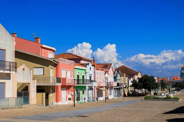 Portekiz, Torreira, 13 Ekim 2025 'te derin mavi gökyüzünün altında sakin bir sahil kasabasında uzanan renkli konut binaları.