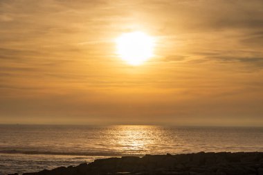 Uzak kum tepeleri ve yumuşak akşam sisi ile Atlantik kıyılarında gün batımı, Portekiz, Ovar Furadouro, 14 Ekim 2025