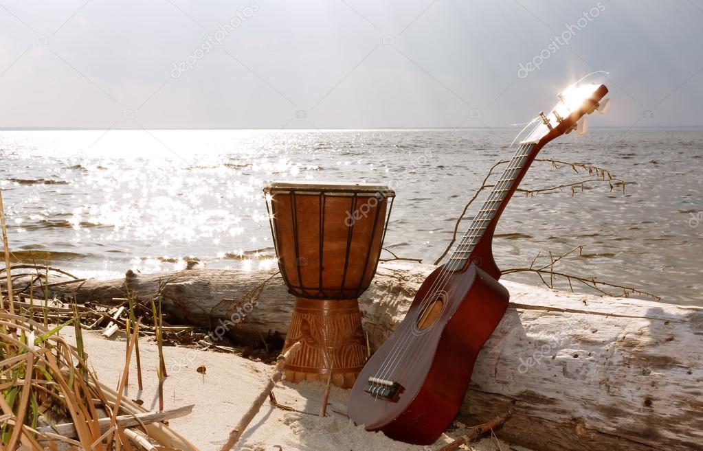 Ukulele & ethnic drum on a beach.