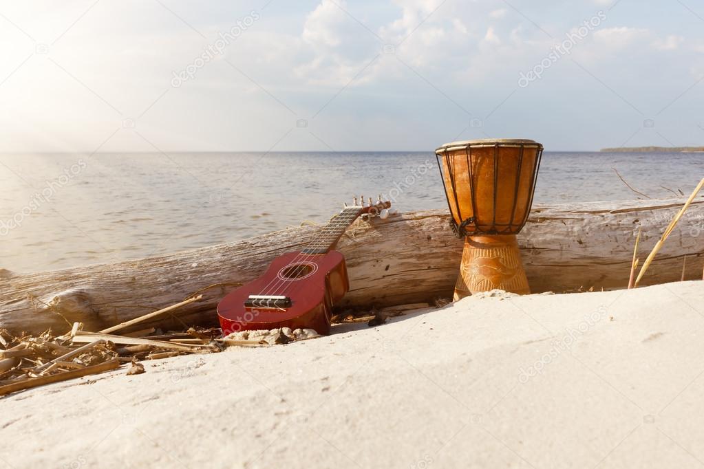 Ukulele and ethnic drum on a sunny beach.