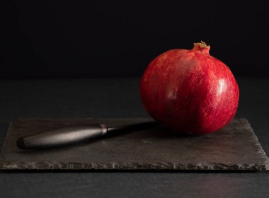 Büyük olgun nar siyah bir arkaplanda yatıyor.