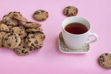 Pembe arka planda bir fincan çay ve bir sürü kurabiye. Aşırı yeme kavramı