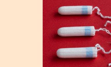 Parlak kırmızı arka planda üç dişi tampon var. Kadın hijyen ürünleri.