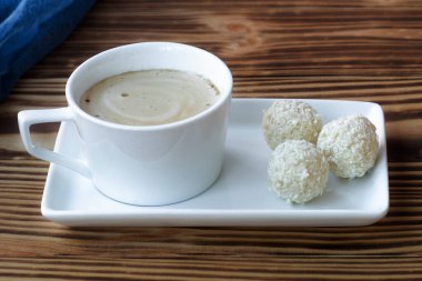 Bir fincan köpüklü latte, ahşap bir masanın üzerinde duruyor. 