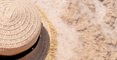 Bir hasır şapka tuzlu beyaz kumların üzerinde yatar. Seyahat kavramı 