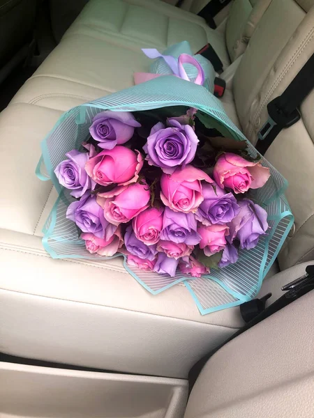 Egy csokor virág fekszik a könnyű bőr hátsó ülésen az autó. — Stock Fotó