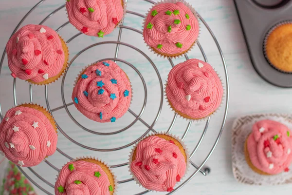 Flache Muffins sind mit leuchtend rosa Sahne und Zuckerdekor dekoriert. — Stockfoto