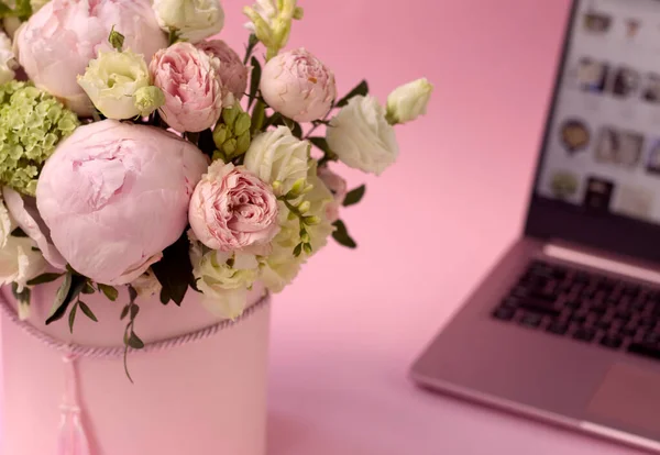 Csokor virág egy dobozban közelkép, a háttérben egy nyitott laptop — Stock Fotó