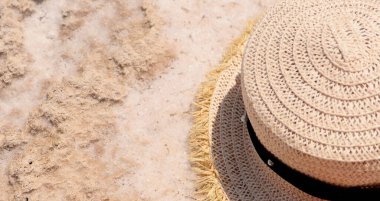 Bir hasır şapka tuzlu beyaz kumların üzerinde yatar. Seyahat kavramı 