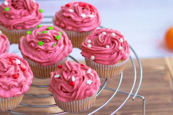 Muffins mit Scharlachcreme und Dekor, Perlen und roten und grünen Sternen. — Stockfoto