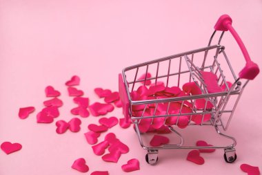 Kırmızı kalpler güzel pembe arka planda alışveriş arabasında şekilleniyor. , 