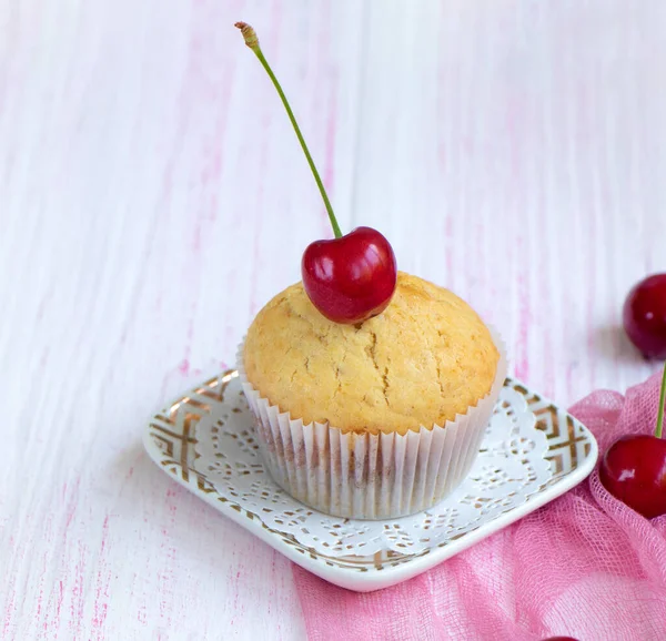 Domácí čerstvý muffin zdobený čerstvými třešněmi stojí na talíři — Stock fotografie