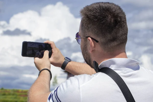 guy with his back turned makes a selfie on the phone.