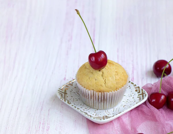 Domácí čerstvý muffin zdobený čerstvými třešněmi stojí na talíři — Stock fotografie