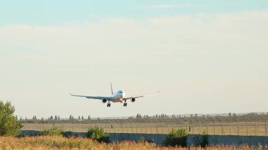 Mavi gökyüzünde, ormanın üzerinden geçen yolcu uçağı, güneş parlıyor. Nakliye, seyahat. Yüksek kalite fotoğraf