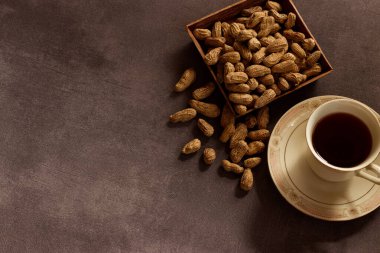 Logo modelleme, ambalaj, markalaşma gibi işler için arka planda yer fıstığı olan bir fincan çay..