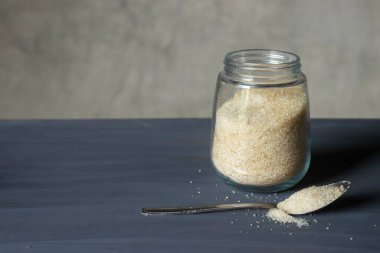 Cam kavanozda granüle şeker ve metal kaşık..