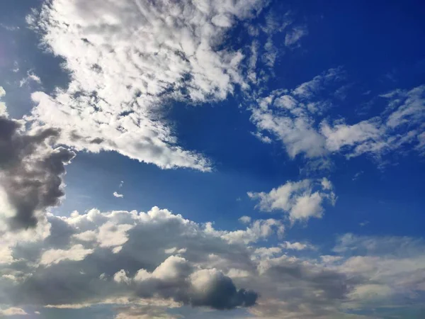 A horizontal shot of bright blue sky with puffy white clouds.