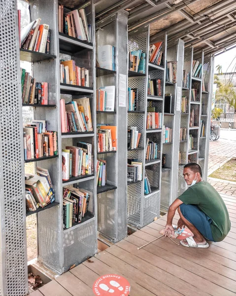 Bedava kütüphanede okumak için kitap seçen adam..