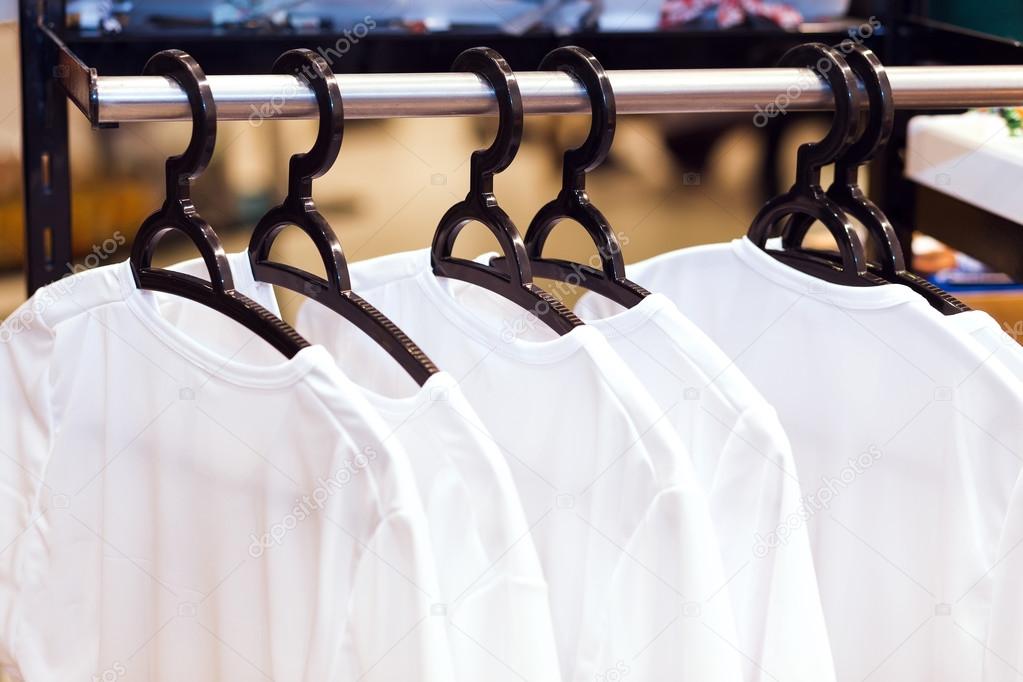 White clothes hanging on hangers in a store