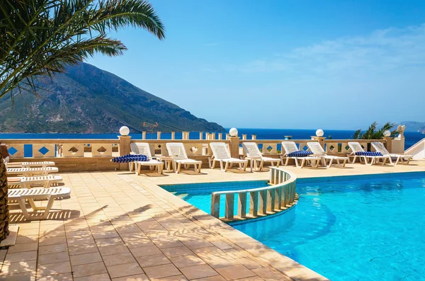 Zwembad en ligstoelen onder palmboom, Griekenland — Stockfoto