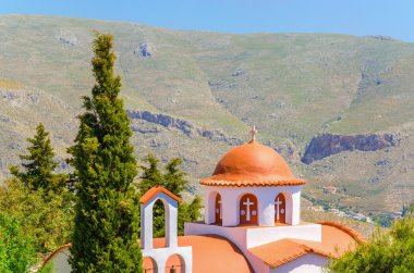 Greek church in mountains with cyprus garden clipart