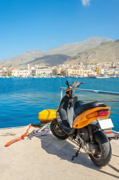 Orange scooter standing on wharf of Greek harbour — Stock Photo, Image