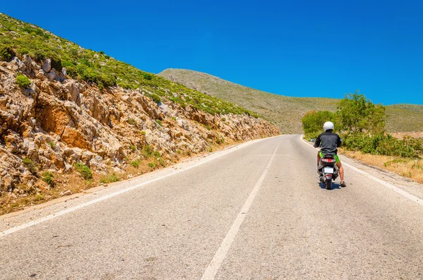 Giovane uomo guida scooter su strada asfaltata vuota — Foto Stock