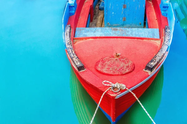 Empty red wooden boat with blue broadside — Stock Photo, Image