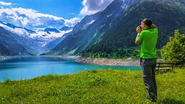 Turista stojí vedle azurové horské jezero — Stock fotografie