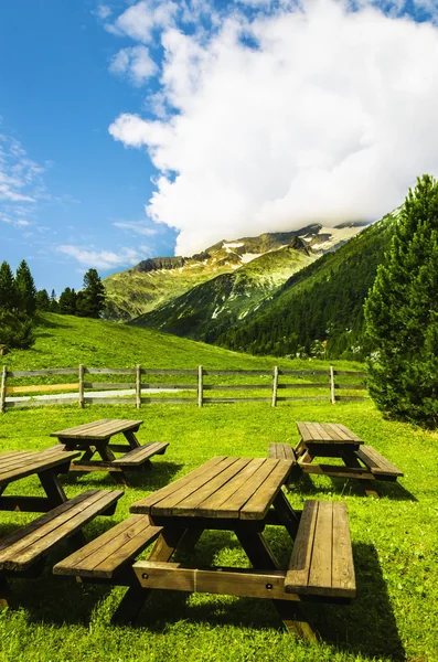 Panche con tavoli nella valle alpina — Foto Stock