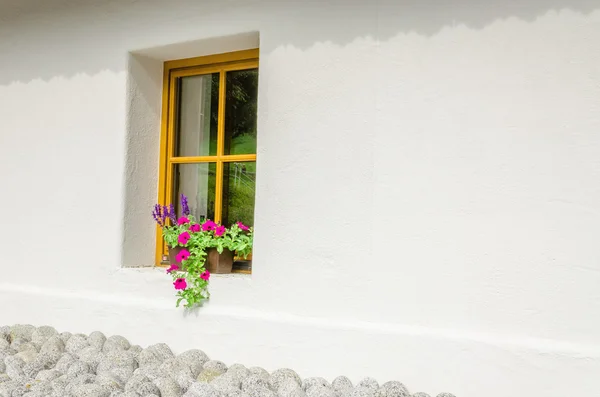 Ventana con geranios morados en una pequeña casa de campo —  Fotos de Stock