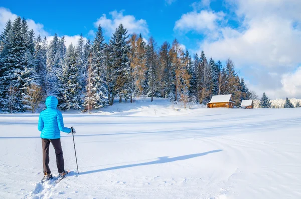 Kvinnan i blå gryning jacka med fjällstuga — Stockfoto