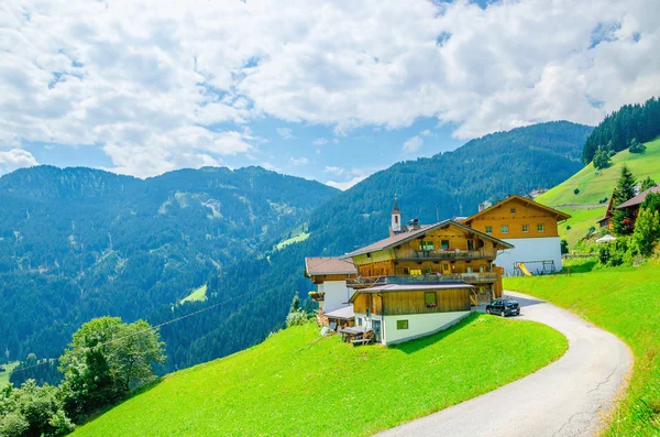 Alpine building with green meadows and high peaks — Stock Photo, Image