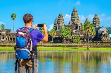 Young man taking photo of Angkor Wat, Cambodia clipart